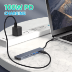 Laptop wordt opgeladen via de 100W Power Delivery poort van de aangesloten USB C hub adapter op een bureau.