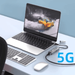 Laptop met racespel op scherm, verbonden via de 5G adapter, tekst "5G" in blauw