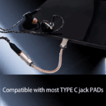 USB-C DAC aangesloten op tablet met professionele oordopjes op donkere achtergrond