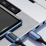 Close-up van de USB-C kabel aangesloten op een zilveren laptop, met een verlicht display dat de stroomtoevoer toont.