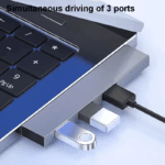 Laptop met hub waarbij drie poorten gelijktijdig in gebruik zijn door diverse USB-apparaten.