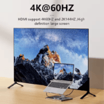 Laptop op een zilveren standaard aangesloten op een groot beeldscherm met 4K 60Hz en 2K 144Hz resolutie.