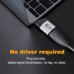 Een compacte grijze adapter aangesloten op een laptop, met de tekst "No driver required" en "Plug and play".