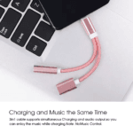 Roze USB-C naar 3.5mm en oplaadkabel liggend op een zilveren laptop