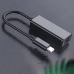 Zijaanzicht van de grijze aluminium USB-C naar RJ45 adapter, liggend op een donker oppervlak