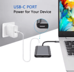 Laptop aangesloten op de hub en een muurlader, toont de pass-through oplaadfunctie via de USB-C PD poort.